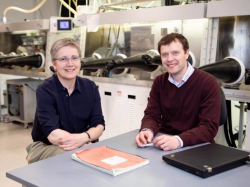 woman and man pose at a desk in a laboratory