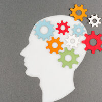 illustration of multicolored gears emanating out of a white silhouette of a person's head