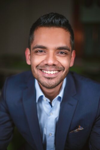 Portrait headshot of a man in a blue blazer, one of our newest distinguished postdoctoral fellows.