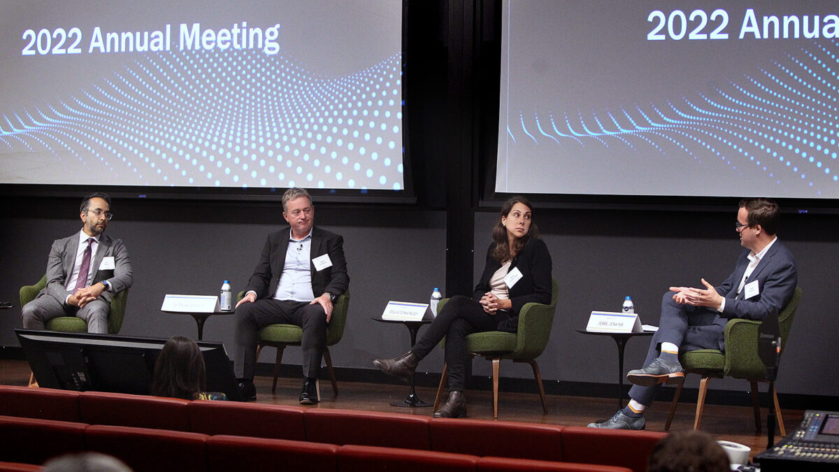 Another panel of 3 men and 1 woman converse on stage.