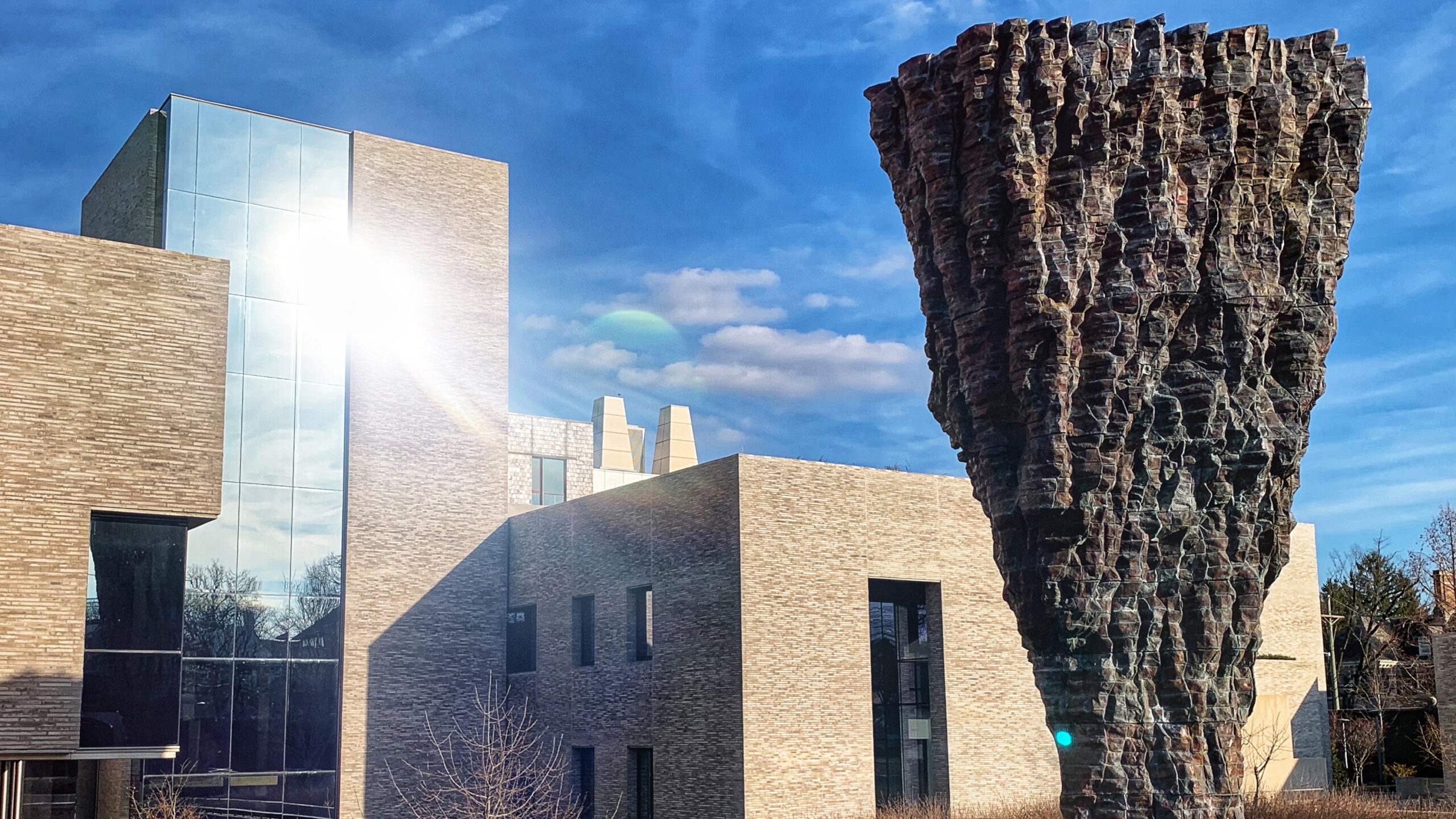 The Andlinger Center with the Uroda statue in the front and the building in the back reflecting a sunflare