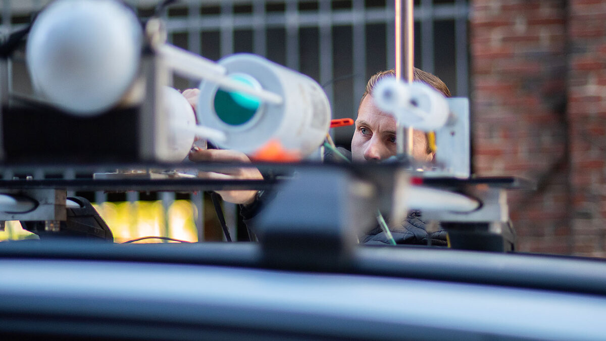 Close-up of a researcher adjusting the methane sensors atop the vehicle.