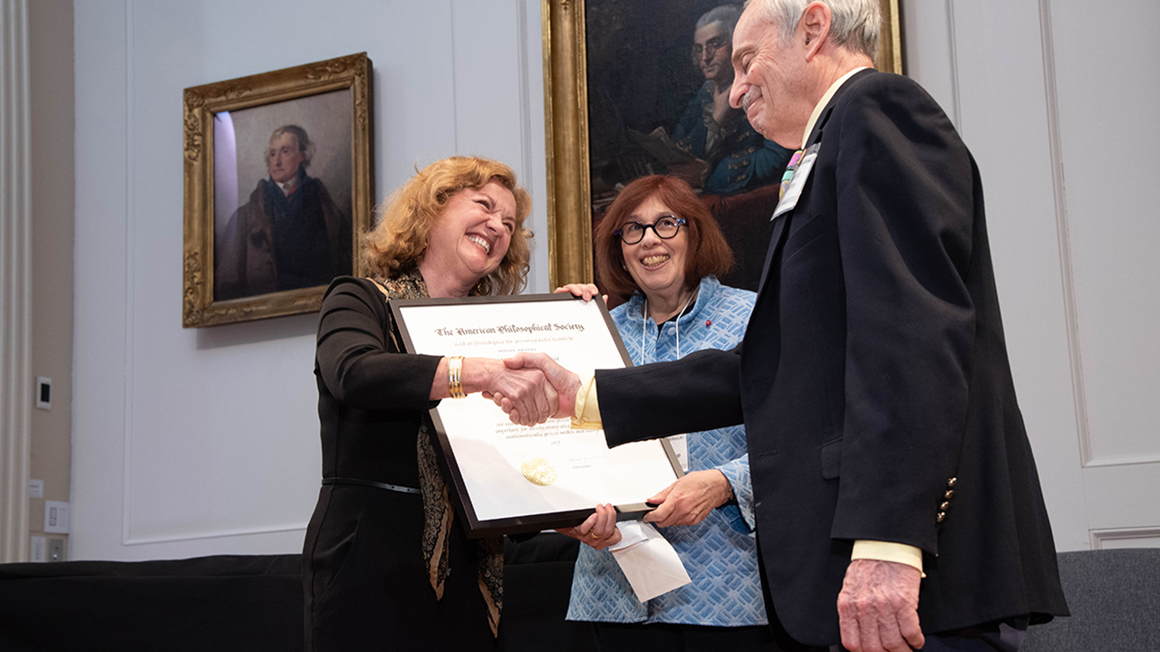 Weber shakes hands with the chair of the selection committee while receiving the award.