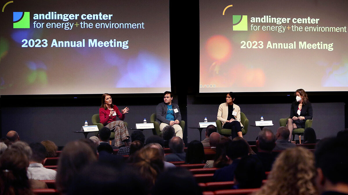 Four individuals are seated on an auditorium stage with dual screens behind them that say Andlinger Center for Energy and the Environment 2023 Annual Meeting.