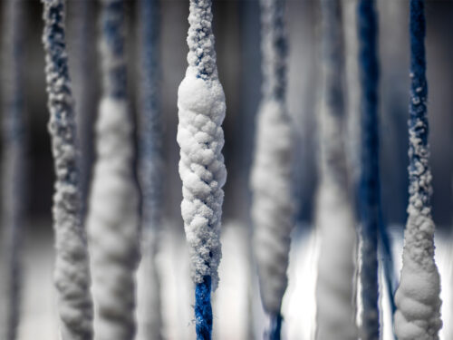 Close up of white salts clumping on blue strings.