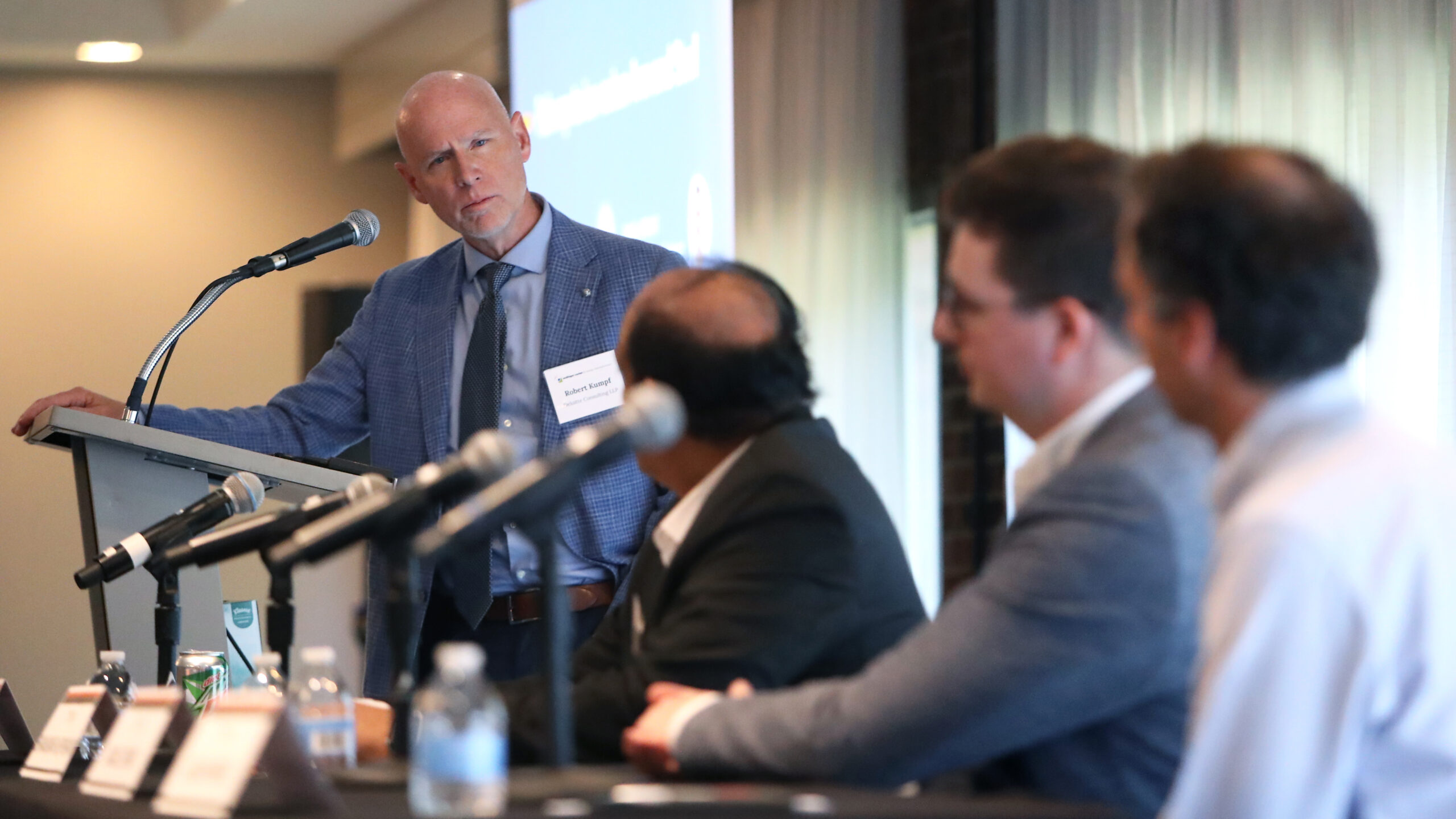 A man at a podium looks at seated panelists