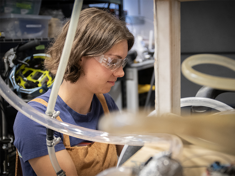 young woman works with pipes and tubing in a lab