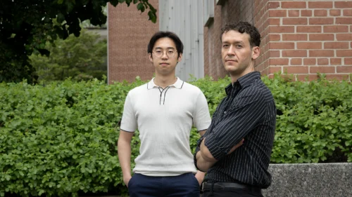 Two men pose in a garden