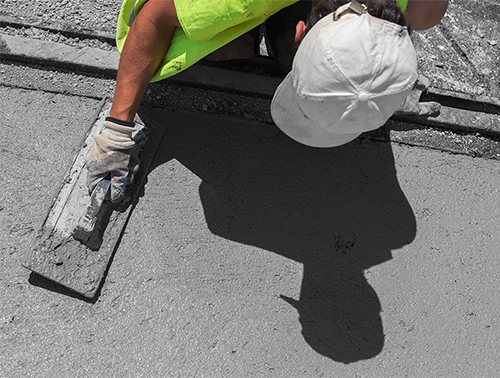 A man smooths cement on the ground
