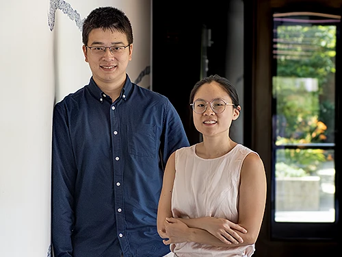 A young man and a woman pose in a hallway