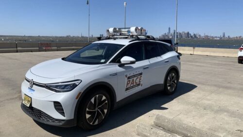 A white electric vehicle with a sensor array on the roof.