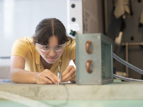 A woman in goggles focuses on a sensor on a table