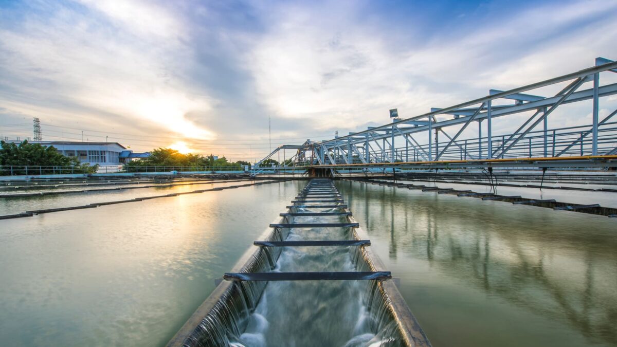 Water treatment facility at sunrise, with reflective pools divided by metal structures.