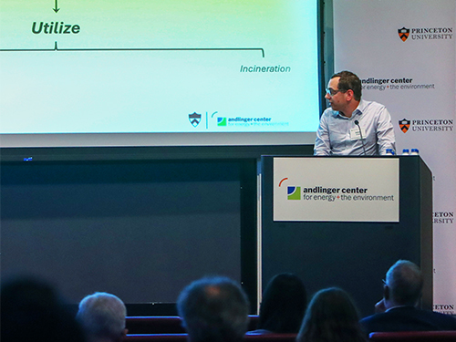 A man stands at a podium with the Andlinger Center logo, presenting a slide. Audience members listen attentively.