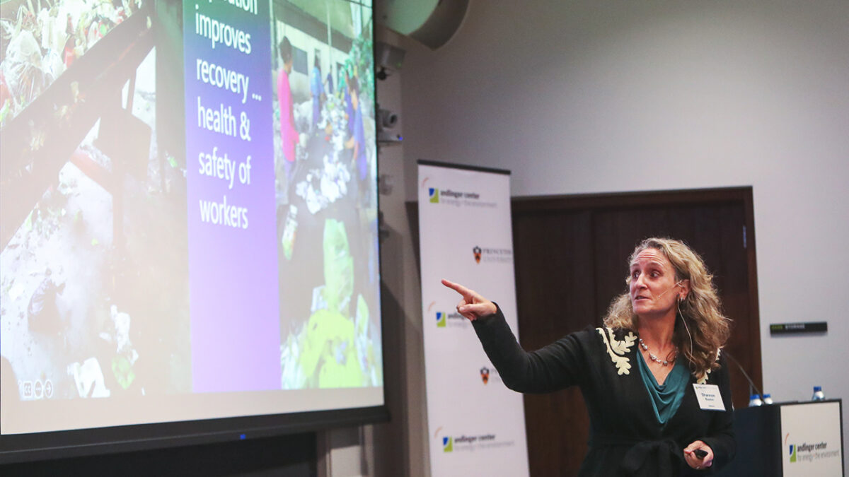 A woman gestures towards a presentation slide showing workers and text on improving recovery and safety.