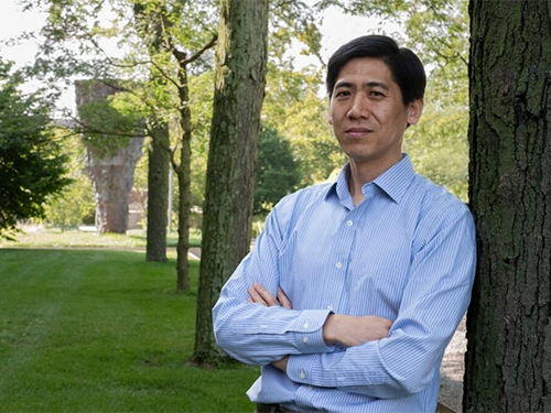 A man leans against a tree