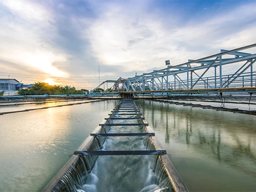 Water treatment facility at sunrise, with reflective pools divided by metal structures.