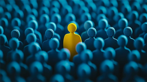 A single yellow figure stands out among a crowd of blue figures, symbolizing individuality and uniqueness. The image conveys a theme of standing out.