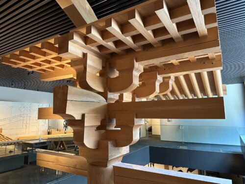 A detailed wooden architectural model showcasing intricate interlocking joints displayed in a modern museum.