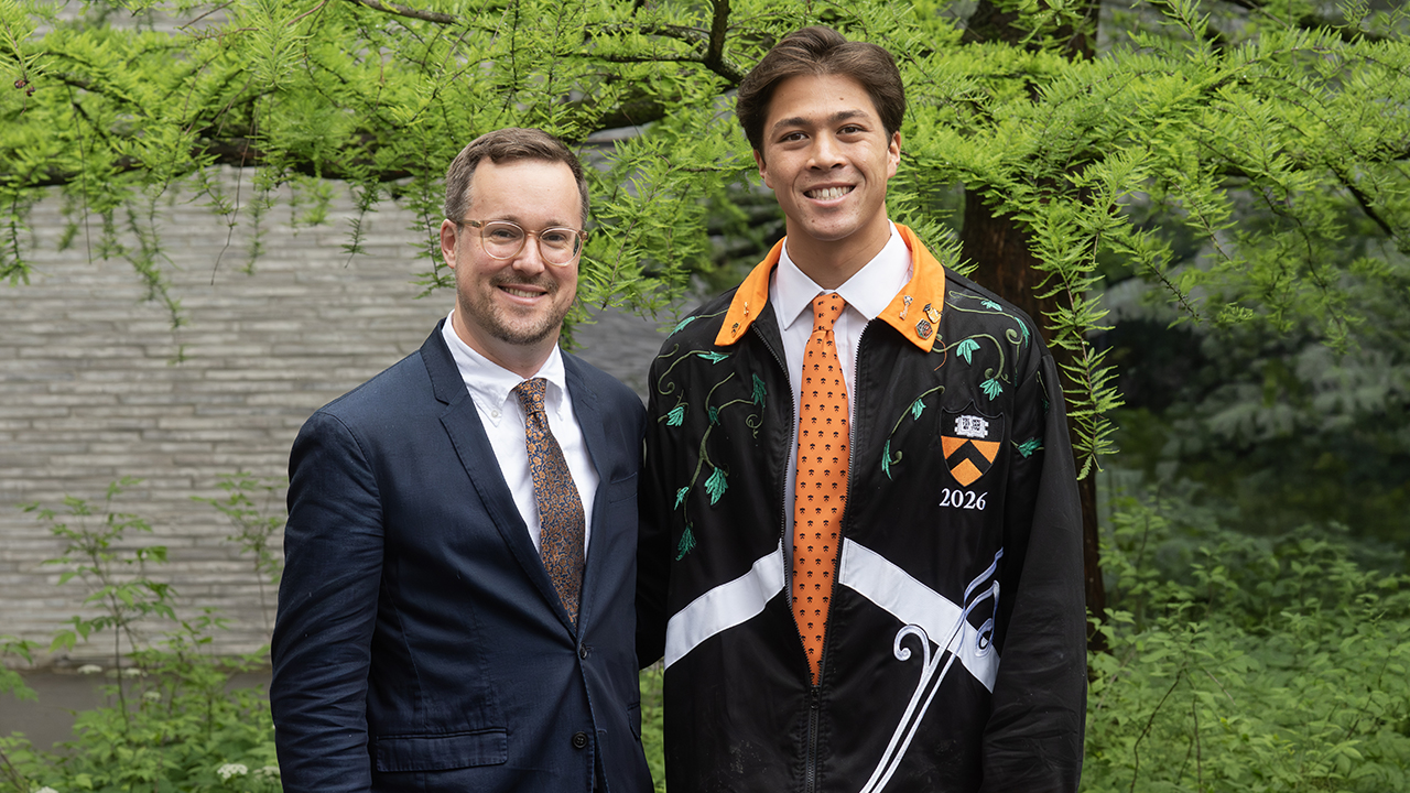 Two men pose in an outside garden