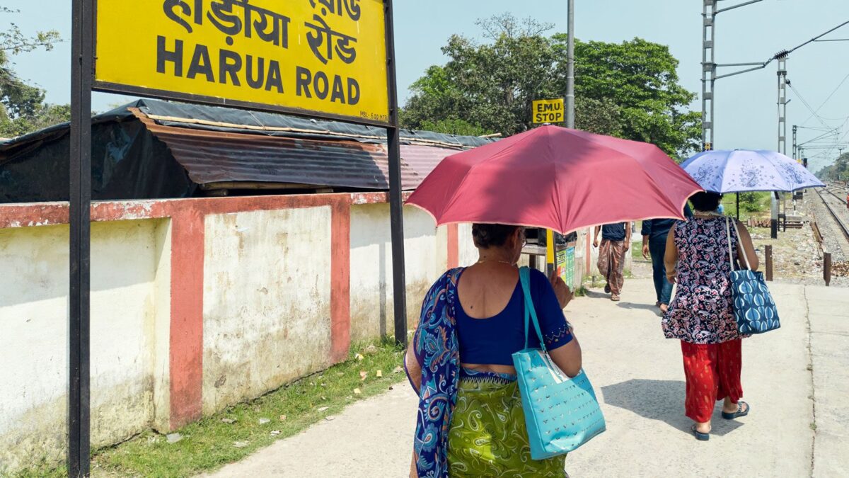Two women in India under umbrellas in the sun